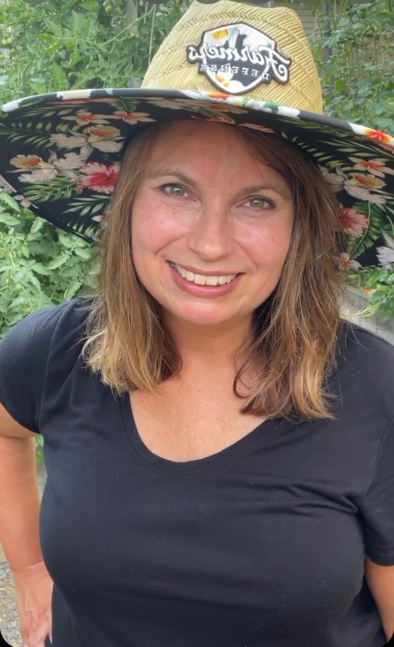 Woman smiling in garden with large brim sun hat