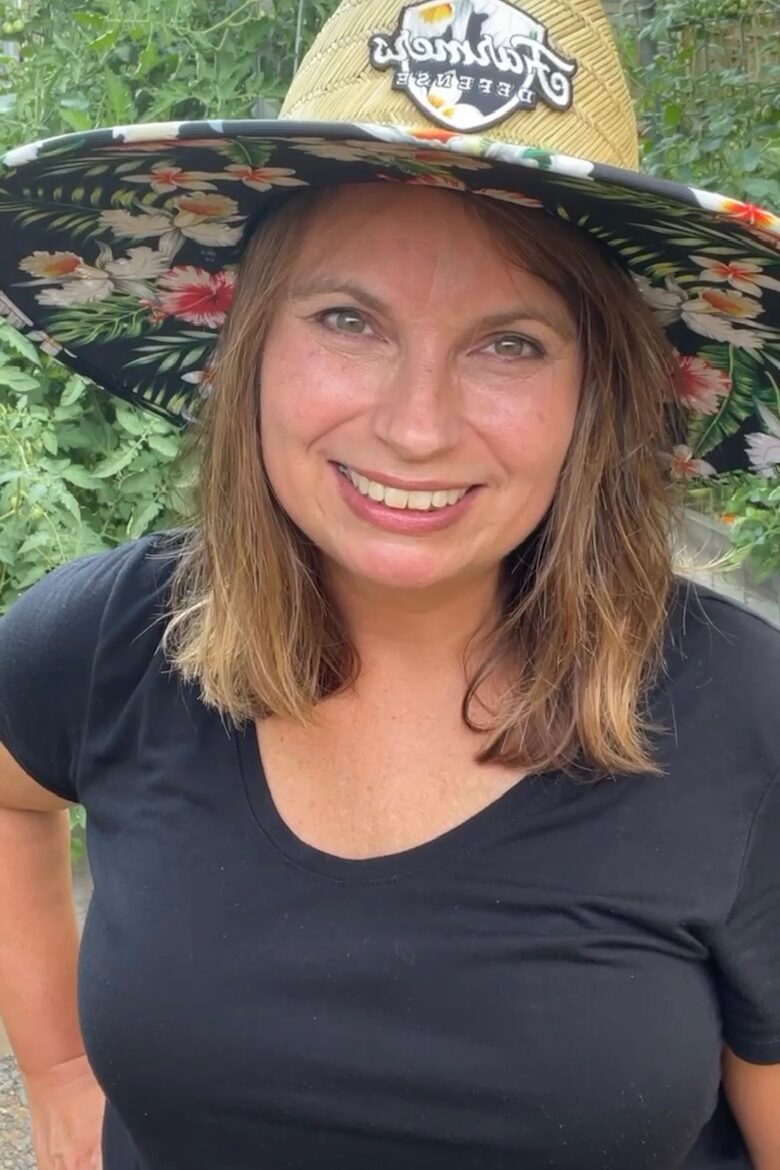Woman smiling in garden with large brim sun hat